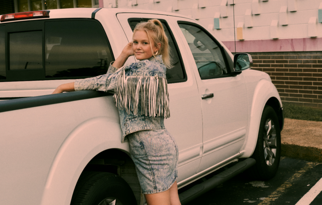 Hailey Whitters leaning on a semi-truck