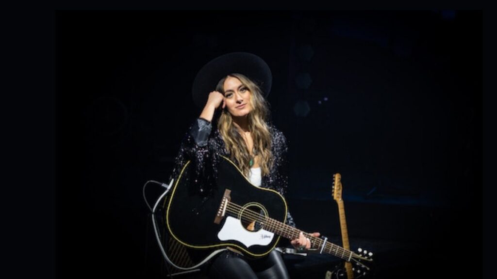 Alyssa Bonagura with a black electro-acoustic guitar