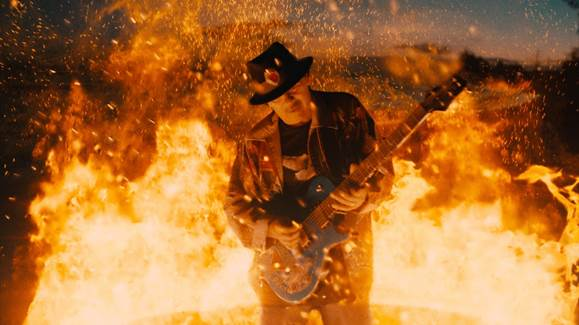 Santana playing guitar surrounded by fire to promote his duet with Rob Thomas