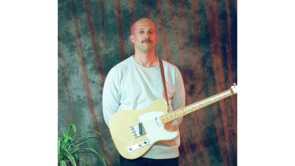 Ian Lake posing with pink hair and a a guitar