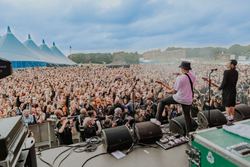 Photograph taken behind a band performing at Slam Dunk festival, showing thousands of people in the crowd