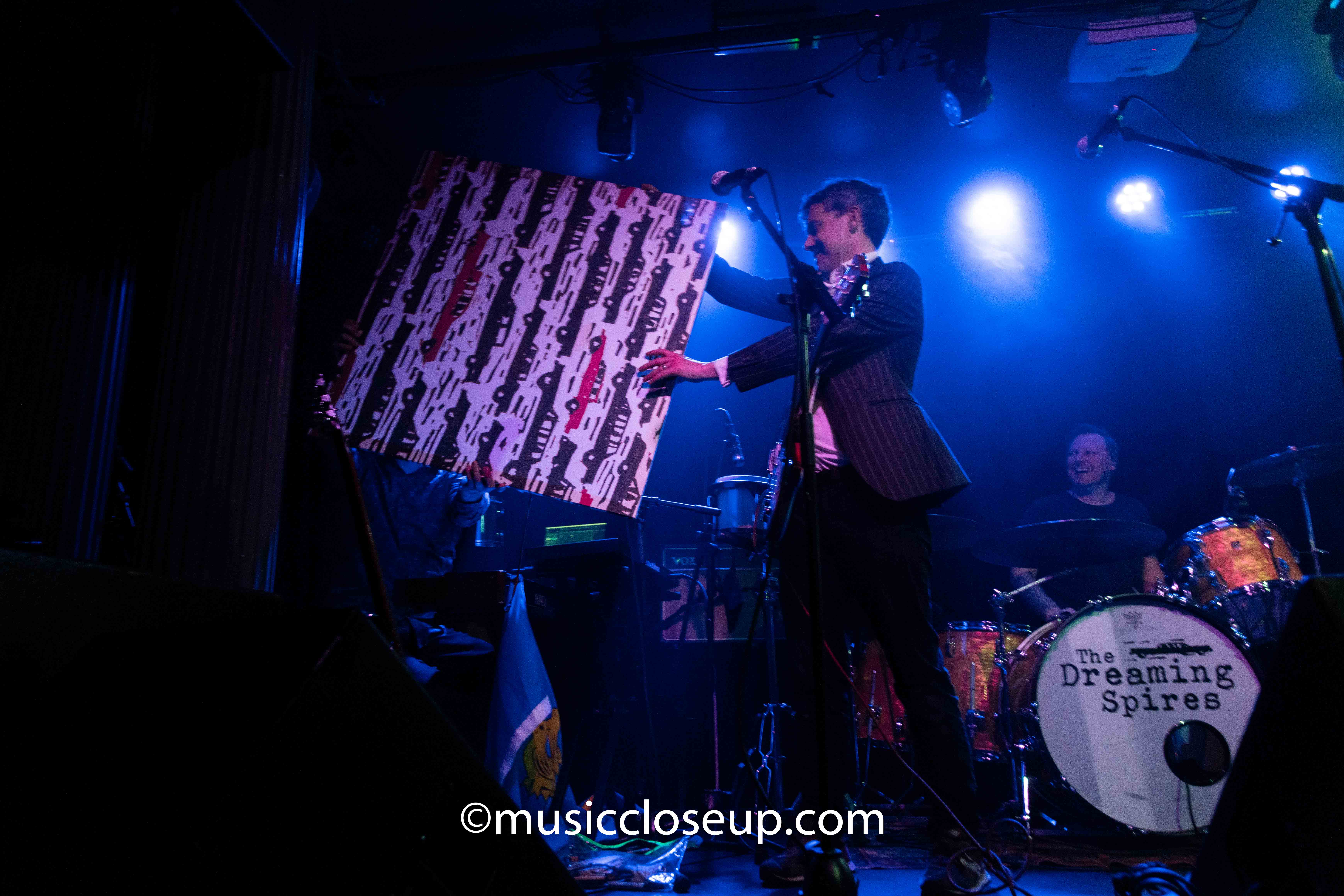 The Dreaming Spires live at The Water Rats: Robin Bennett handing Thomas Collison a keyboard screen decorated with illustrations of cars