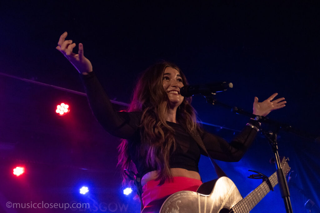 Tenille Townes live in Glasgow: Tenille throws her hands into the air in surprise, smiling at the crowd's reaction to her concert.