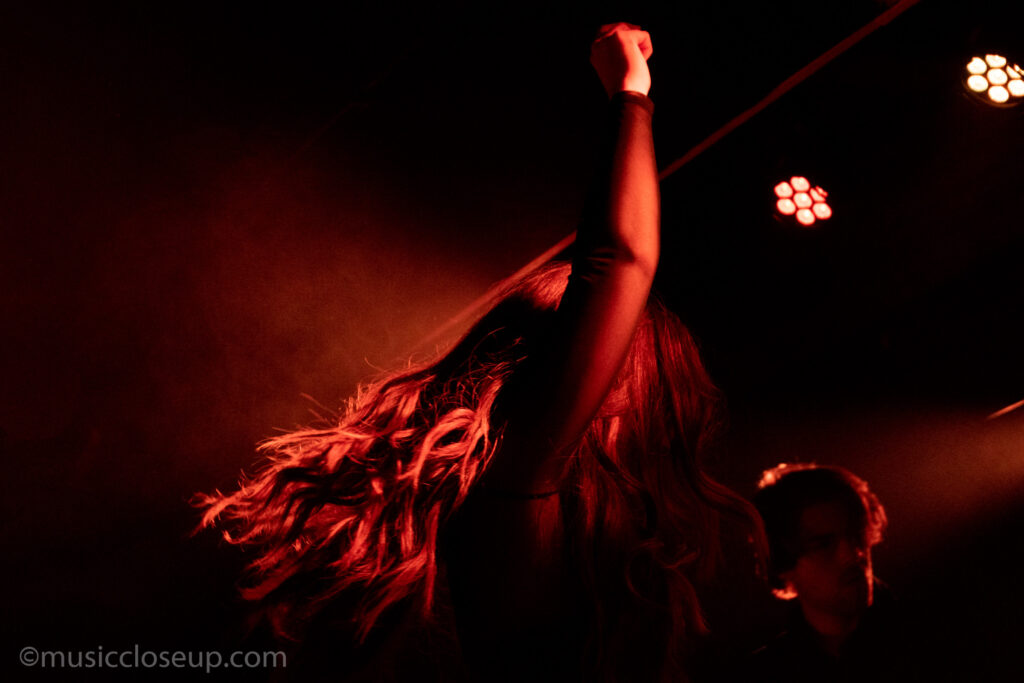 Tenille Townes live in Glasgow: a moody, almost silhouetted photos of Tenille. Her face is obscured by hair and her arm is punched high into the air. 