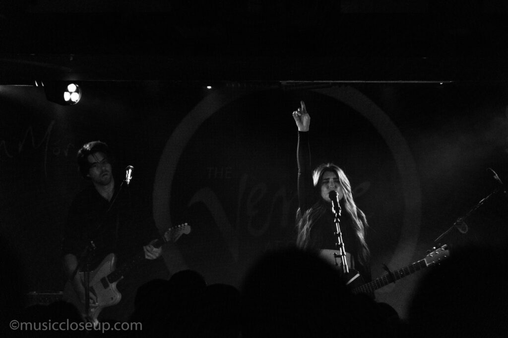 Tenille Townes live in Glasgow: a black and white photo of Tenille pointing her hand to the scky, and a man playing electric guitar next to her.