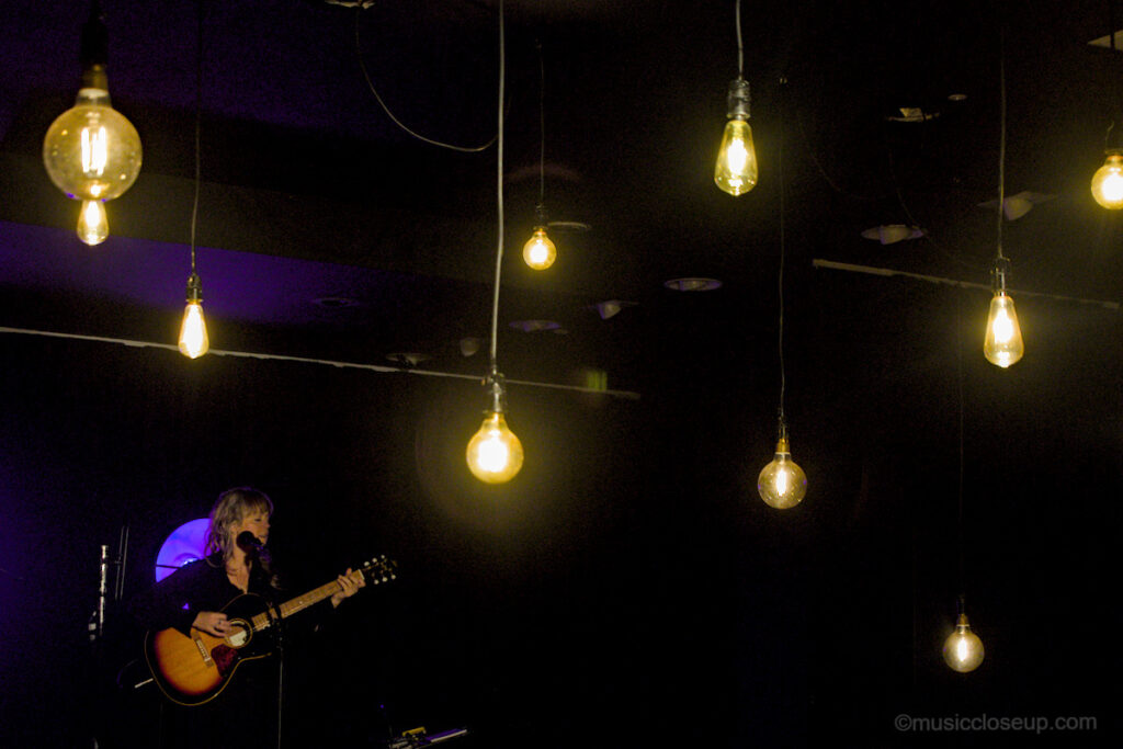 Emily Barker live in Dumfries with hanging lights bulbs in the foreground