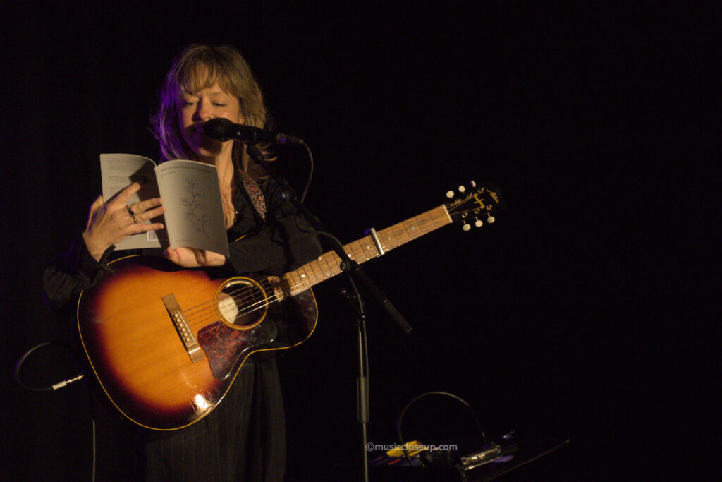 Emily Barker live in Dumfries reading a book of poetry on stage