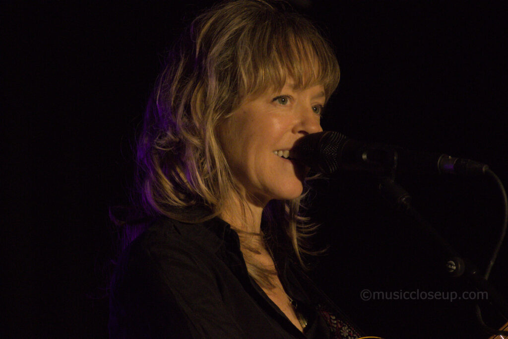Emily Barker smiling while telling a story on stage in Dumfries