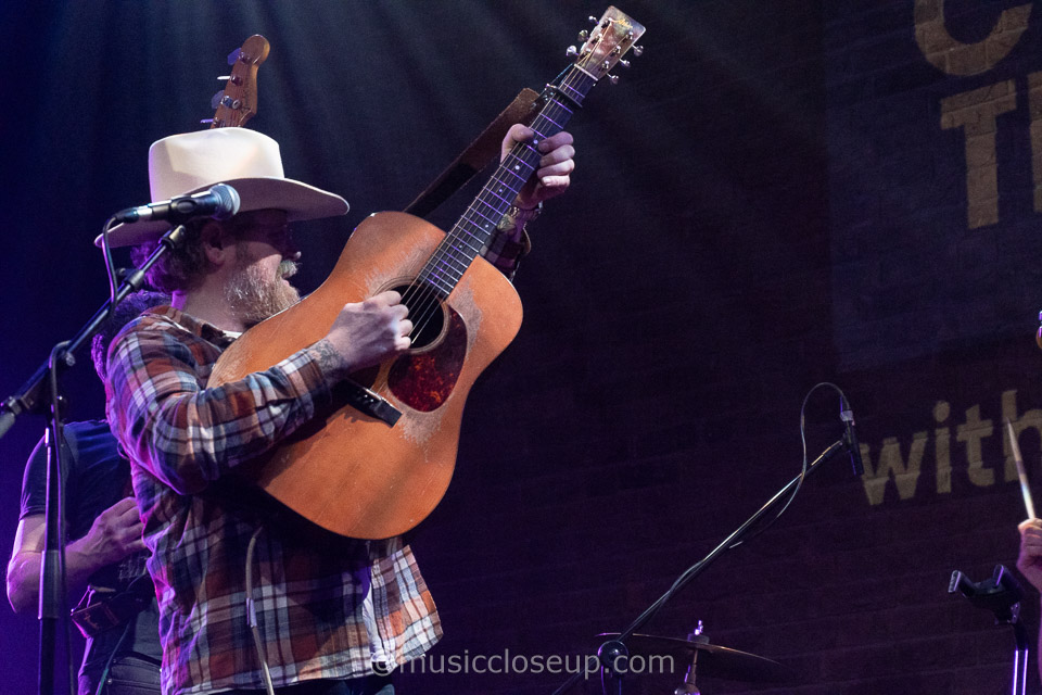 Danny and the Champions of the World live: Danny George Wilson holding his guitar high, wearing a cowboy hat