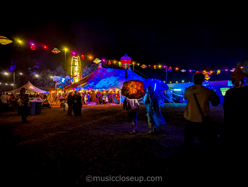 Shambala Festival 2025 review: festival goers carrying colourful, LED lit umbrellas walking towards a lit up stage
