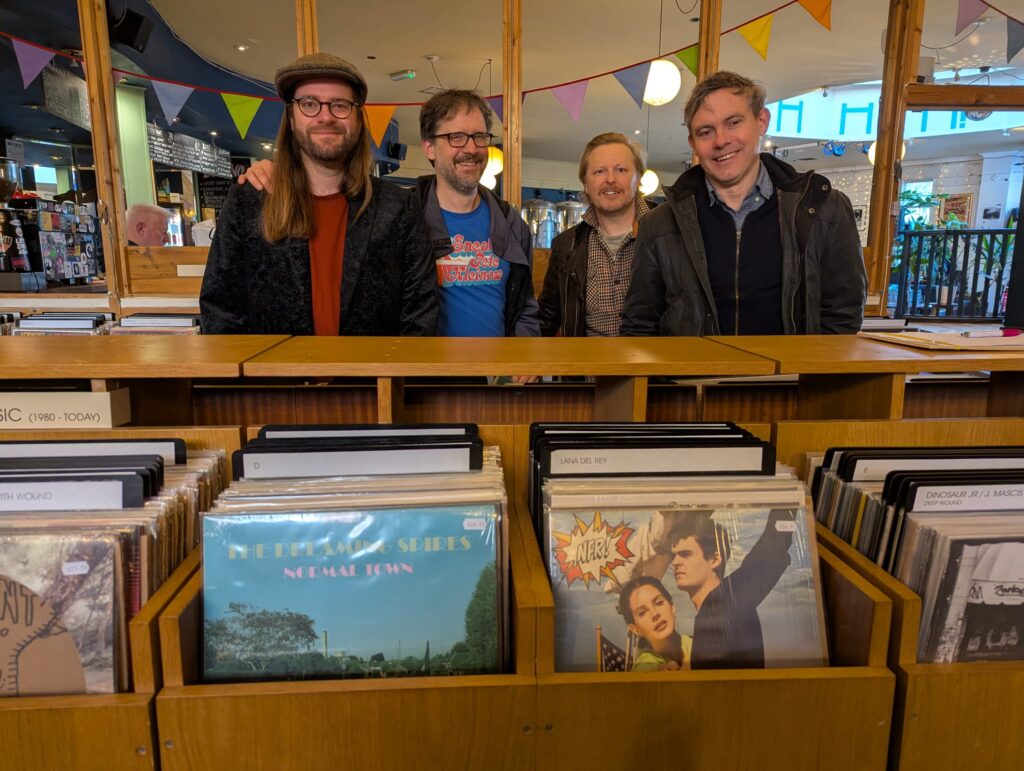 The Dreaming Spires live in Glasgow: four make band members in a record store standing behind a rack displaying their new record.
